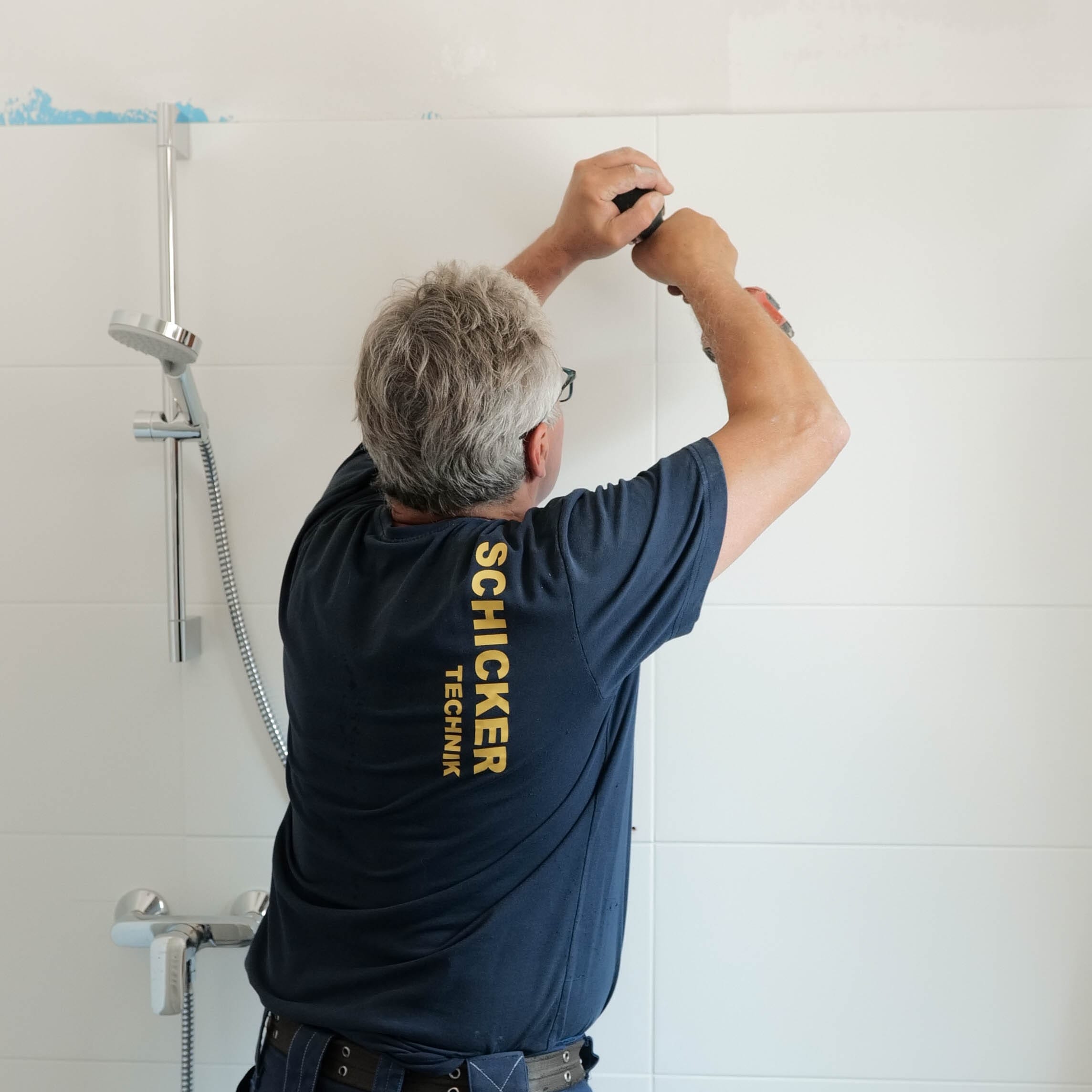 Bild: Techniker bei der Installation eines Duschkopfes im Badezimmer.