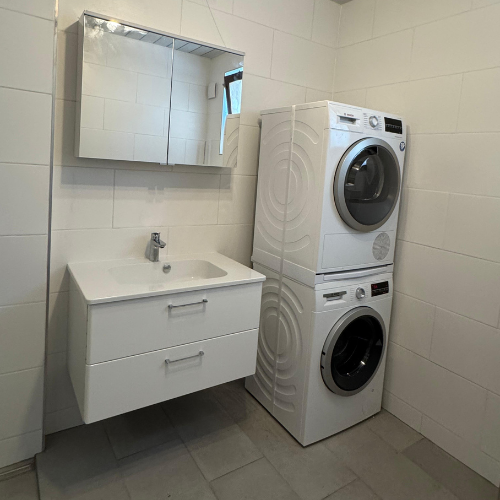 Badezimmer mit Waschmaschine und Trockner nebeneinander.
