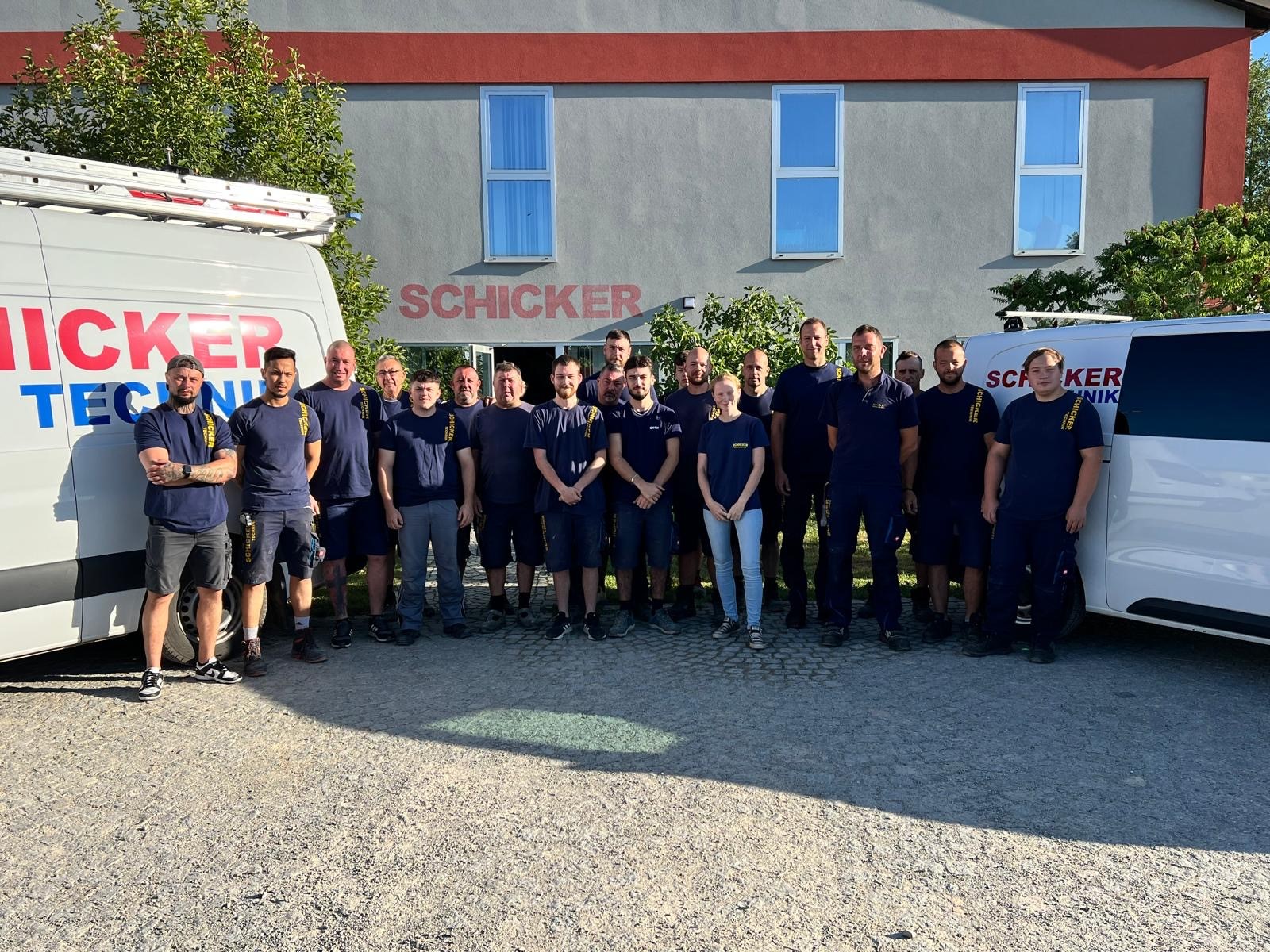 Team Schicker Technik vor Firmengebäude und Fahrzeugen